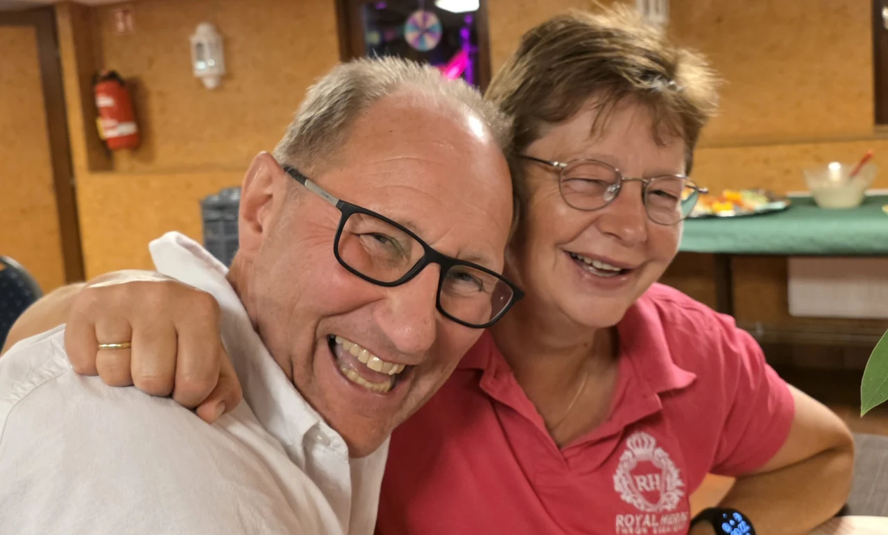 Zwei Gäste lachen Schulter an Schulter im Saal