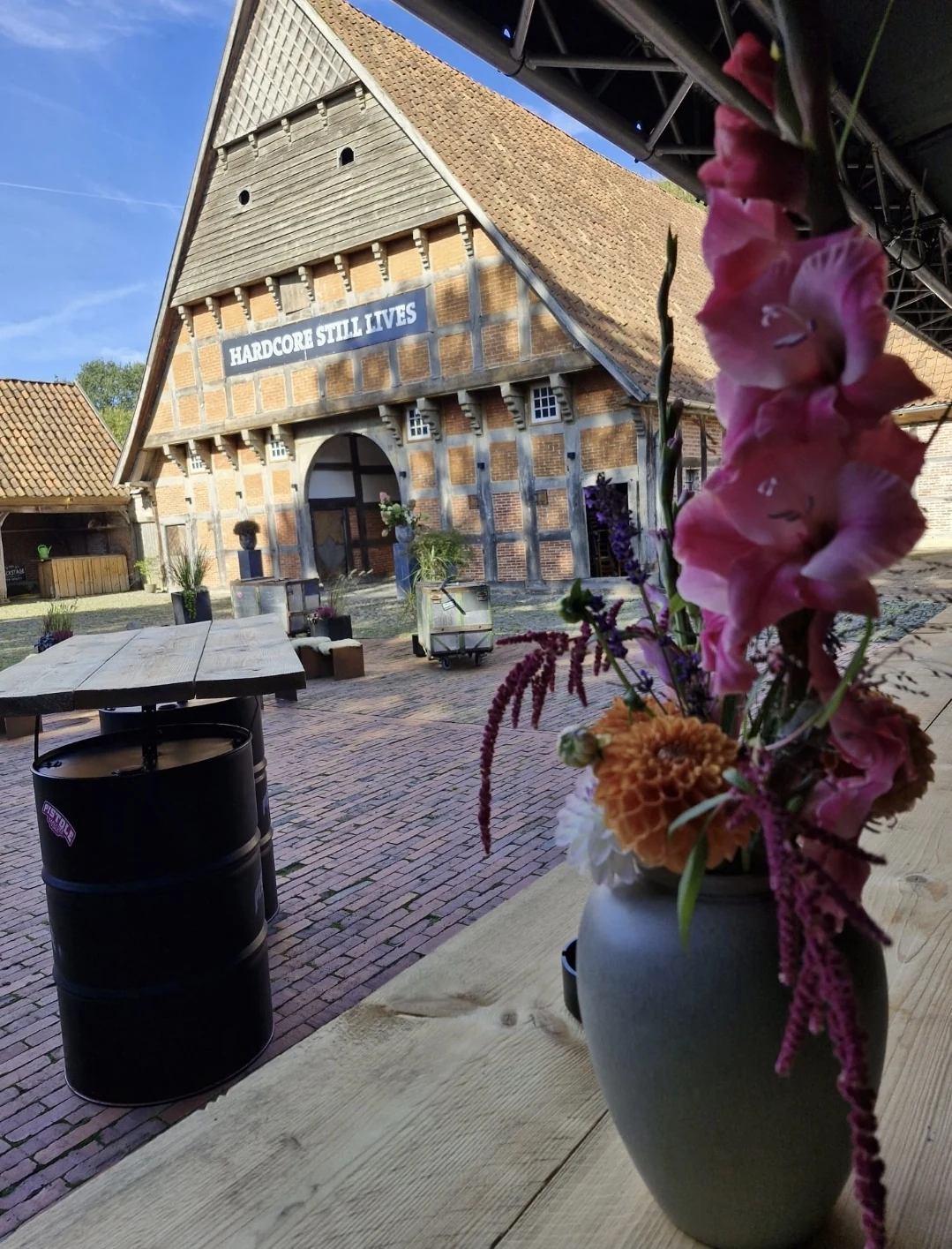 Die Fachwerkfassade mit dem Schriftzug „Hardcore still lives“ hinter dem Blumenstrauß